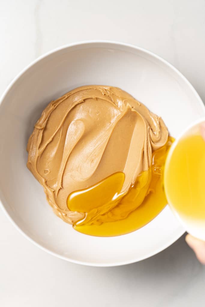 Pouring honey into a bowl with peanut butter.