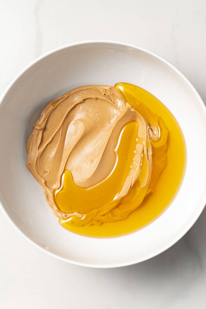 White bowl with peanut butter and honey.
