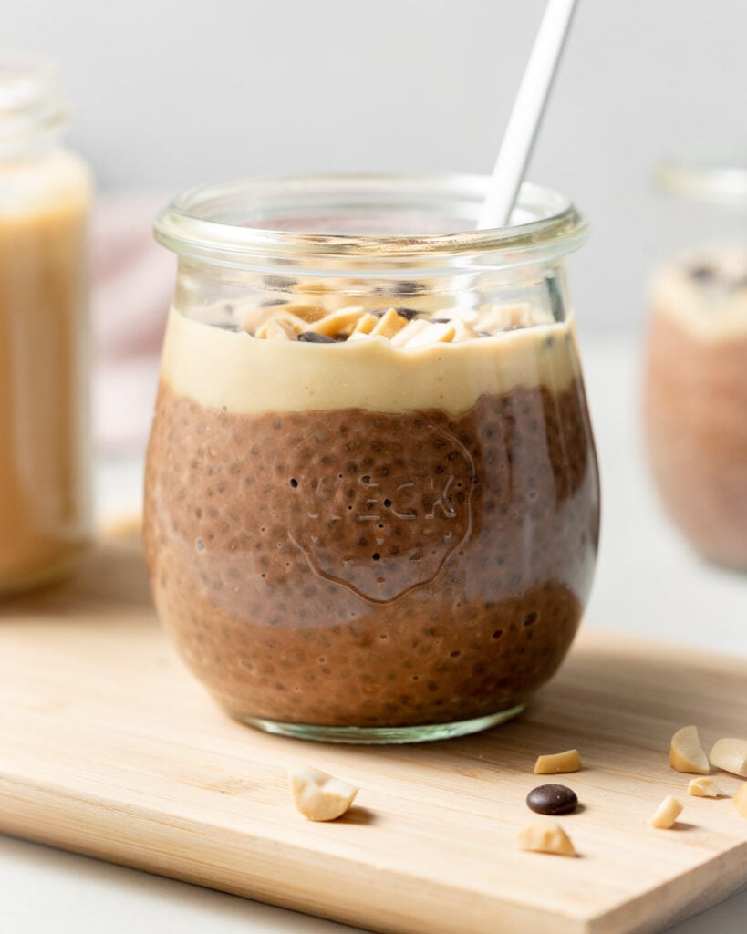 Side shot of a jar of peanut butter chia pudding topped with peanut butter and chocolate chips.