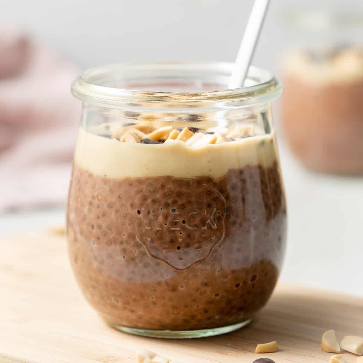 side shot of a jar of chocolate chia pudding topped with peanut butter and chocolate chips
