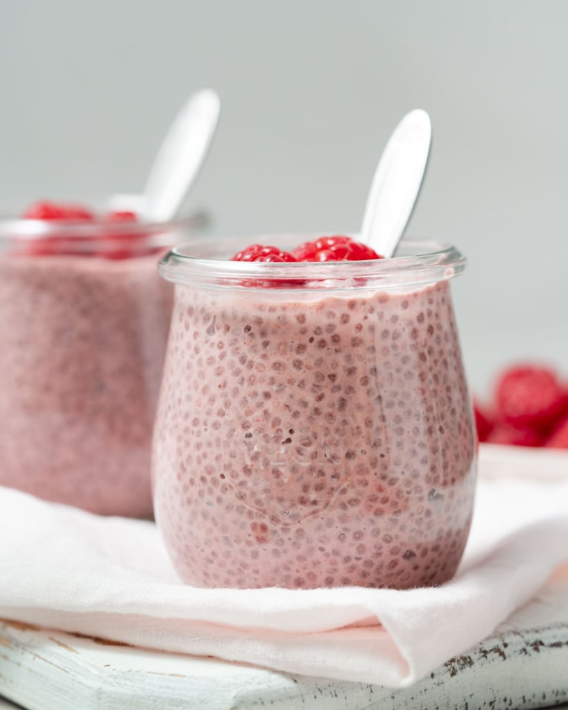 side shot of chia pudding in a jar thats pink in color with spoon in jar