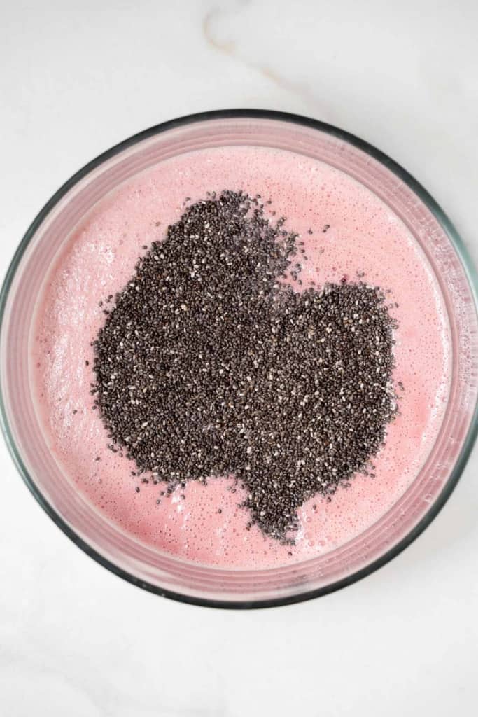 chia seed added over blended raspberry and milk