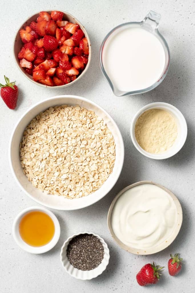 Oats, yogurt, chopped strawberries and honey divided into small bowls.