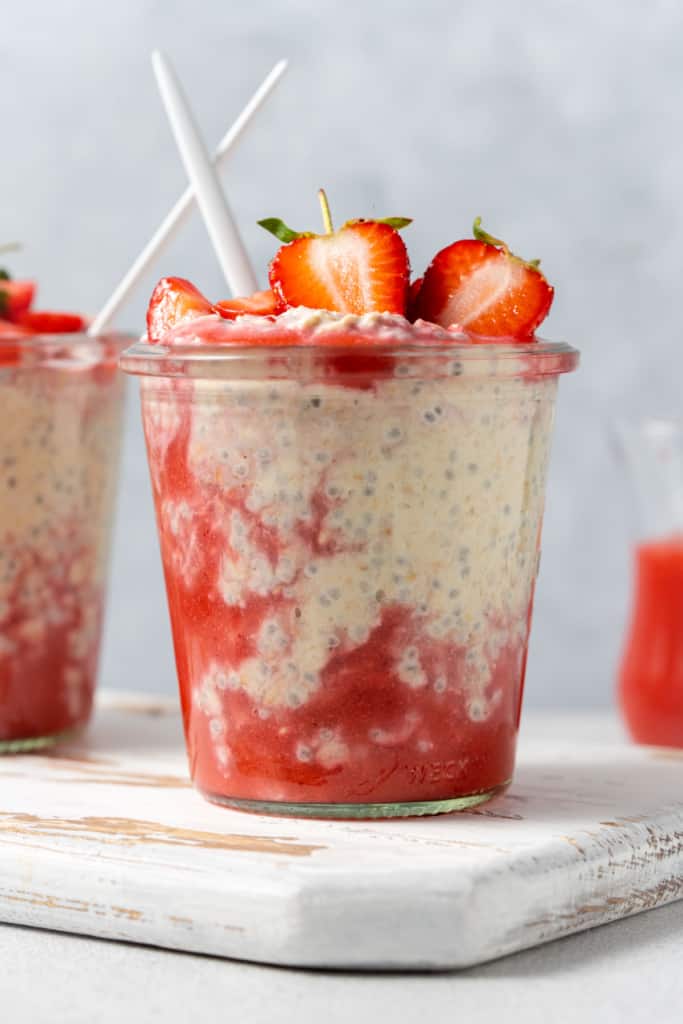 Side shot of a jar with overnight oats and blended fresh strawberries.