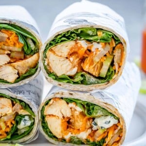 side shot of 4 half chicken wraps on a plate stacked over each other