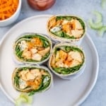 half chicken sandwich wraps on a white round plate.