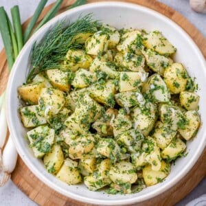 top view potato salad with green herbs in a white round bowl