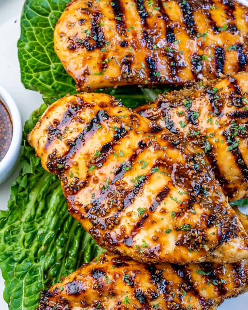 close up view of grilled chicken breast on a plate with green lettuce