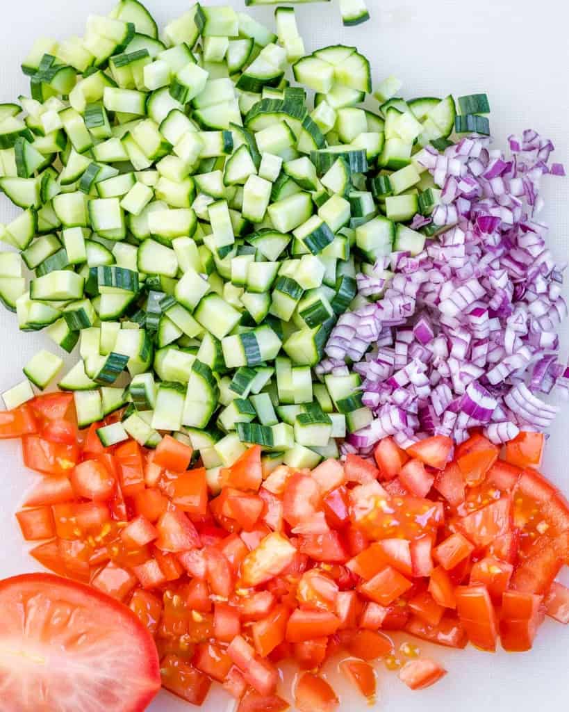 chopped cucumber, onion, and tomato on a cutting board