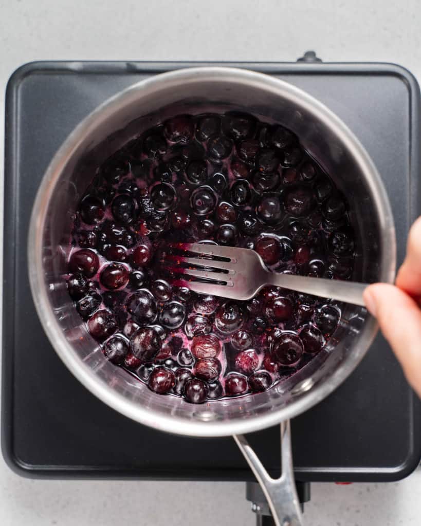 Mashing blueberries with a fork.
