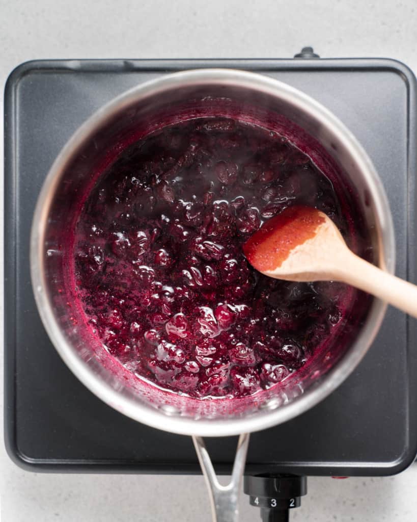 Stirring blueberries in a saucepan.