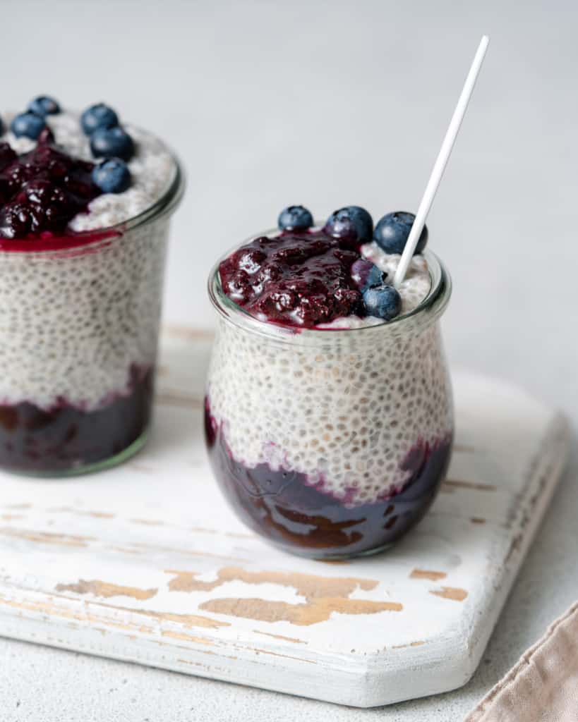 Chia seed pudding layered with blueberry sauce in small glass jars.