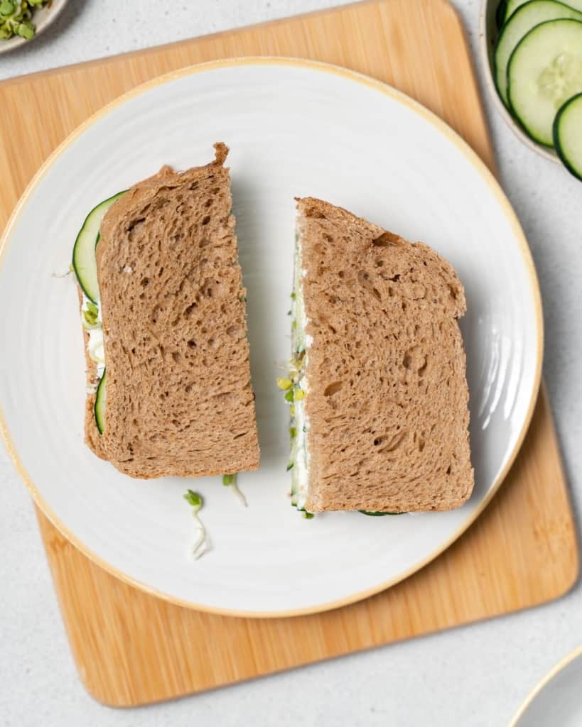 Serving a cucumber sandwich on a white plate.