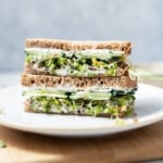 side shot of cucumber sandwich sliced in half on a plate