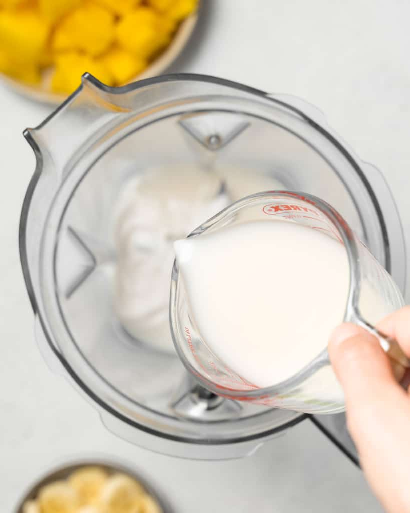 Adding milk and yogurt to a blender.