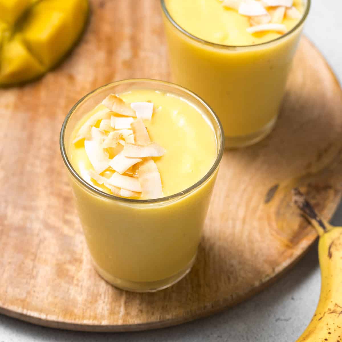 side shot of mango smoothie in a cup topped with toasted coconut
