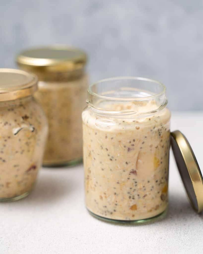 Adding overnight oats to glass jars with lids.