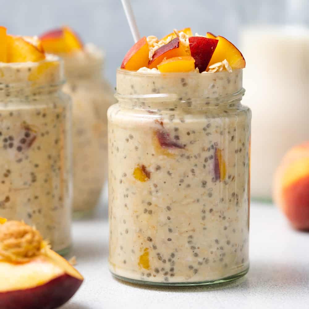 Side shot of overnight oats in a jar topped with chopped peaches.
