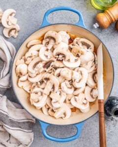 Sliced mushrooms are added to a pan.