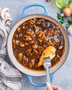 Chicken is being added to the mushroom sauce in the pan.