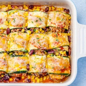 top view enchilada roll ups with zucchini and topped with melted cheddar cheese