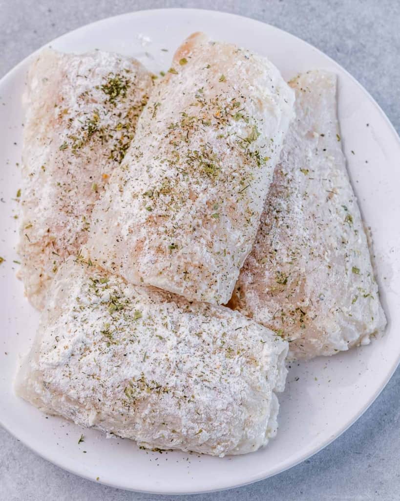 seasoned fresh uncooked cod on a plate 