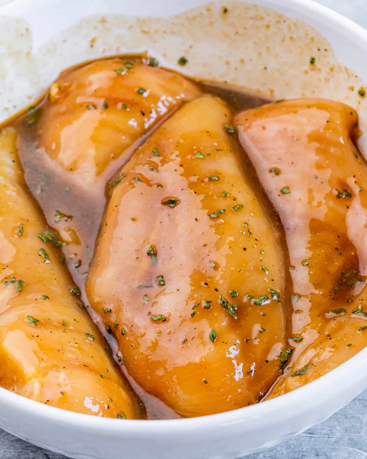 Marinating chicken breasts in a brown sauce.