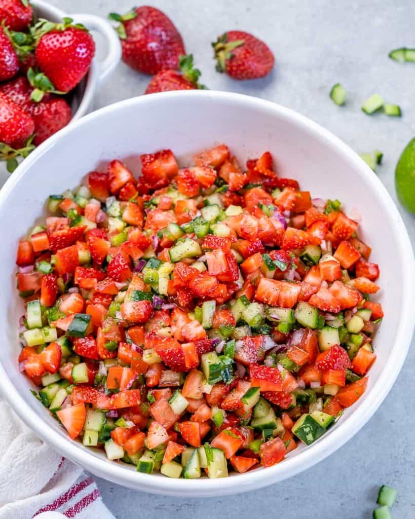 Strawberry salsa mixed with cucumbers and cilantro in a white bowl.