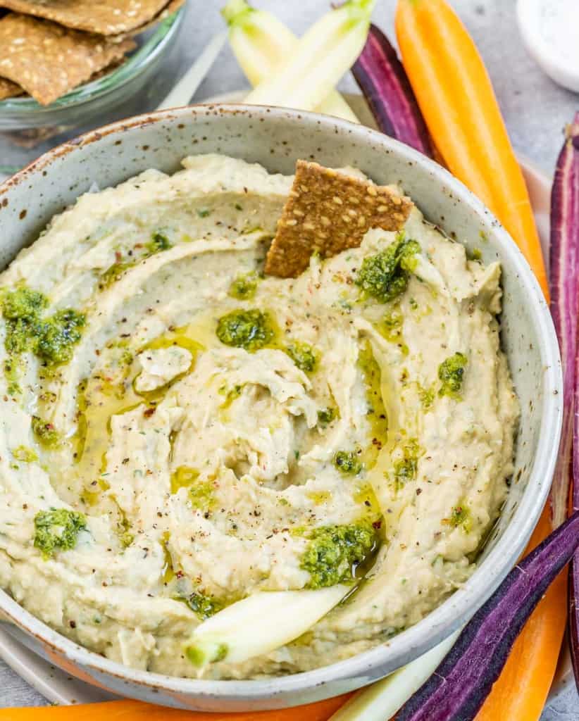 White bean dip garnished with pesto in a small bowl.