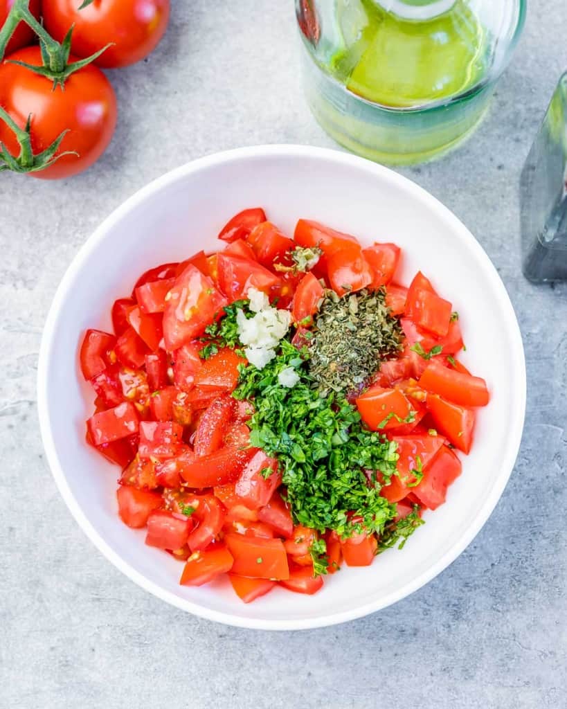 chopped tomatoes, herbs, and parsley added over a plate 