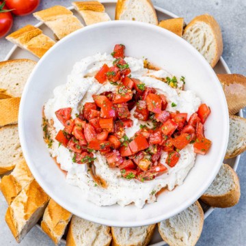 top view whipped ricotta cheese in a white bowl topped with tomato balsamic mix