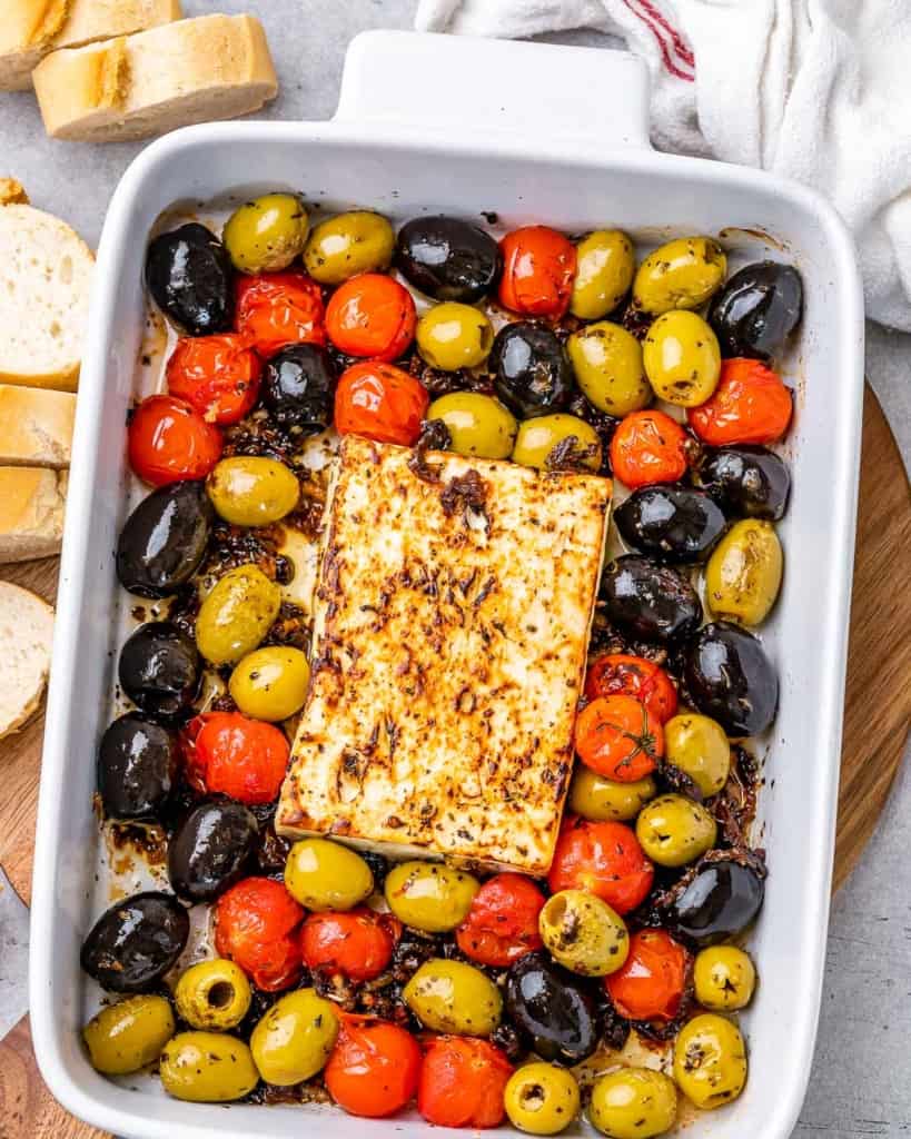 top view dish with baked feta cheese, olives, and tomatoes