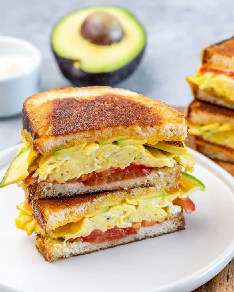 Breakfast sandwich made with egg, tomato, avocado and cheese.