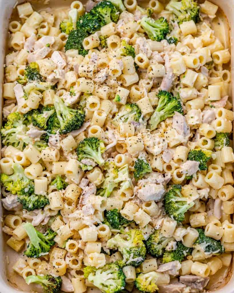 top view close up image of chicken alfredo baked in a dish with broccoli
