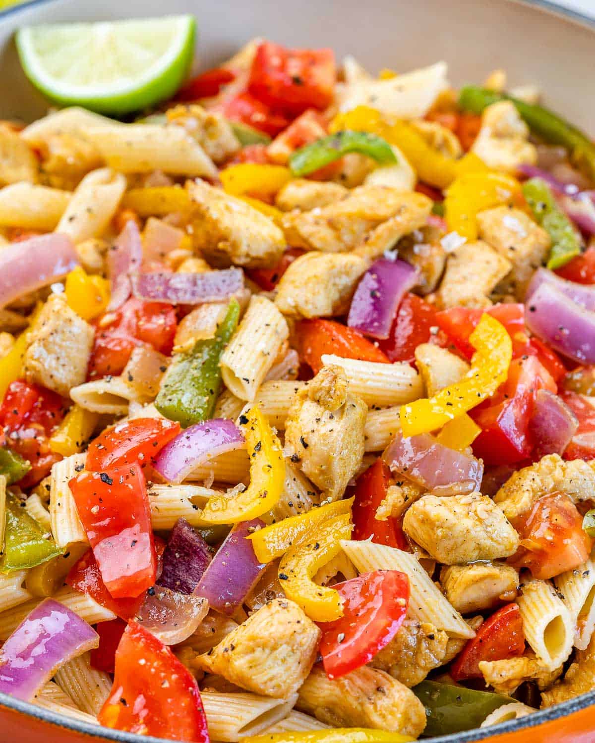 Closeup of seasoned chicken pieces cooked with red onion and bell peppers.
