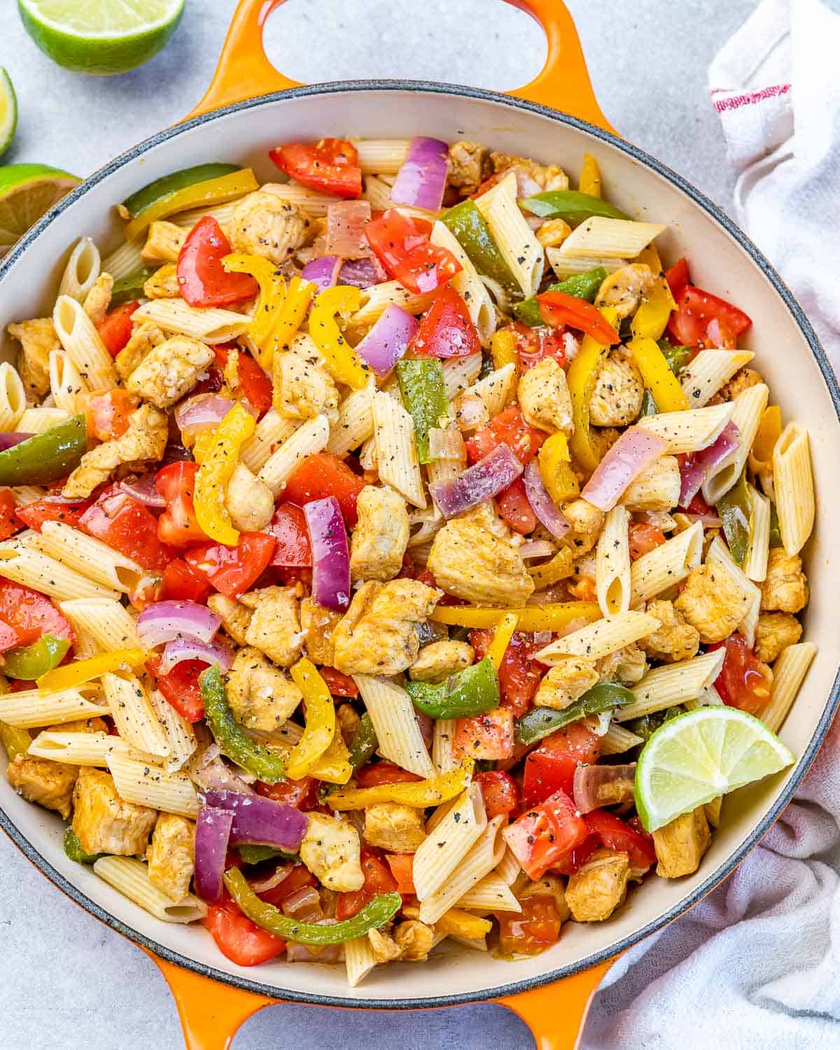 top view orange skillet with chicken and pasts with fajita veggies