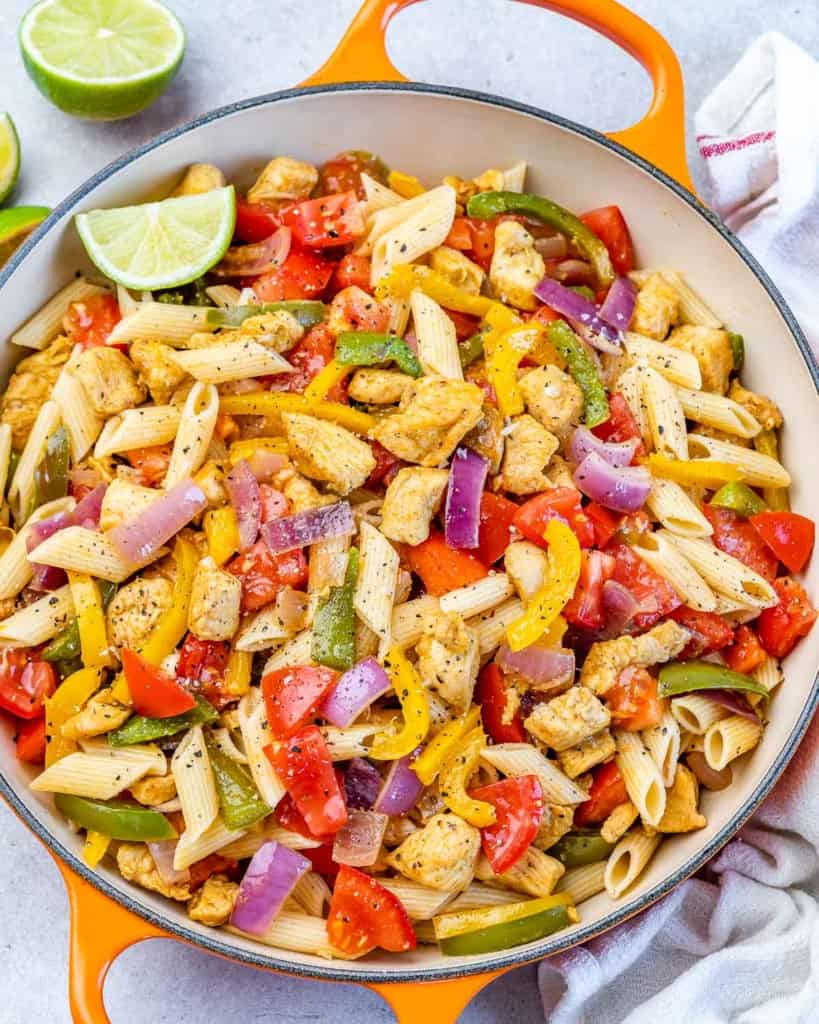 Chicken fajita pasta served in a skillet with a wedge of lime.