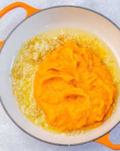 Adding pumpkin to sautéed shallots.