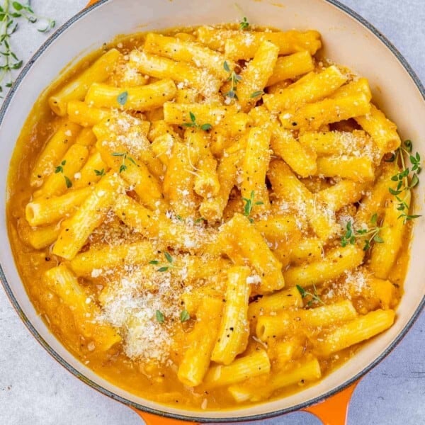 Garnishing pumpkin pasta with parmesan cheese and fresh thyme.