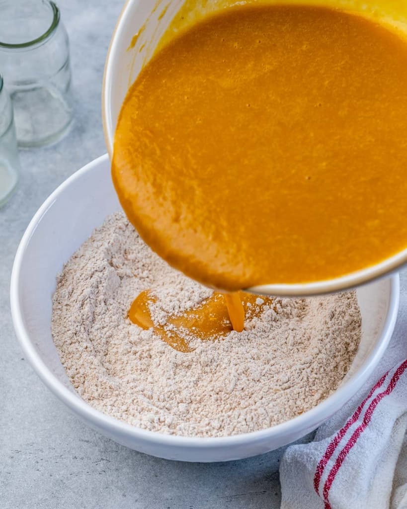 Pouring pumpkin puree mixture over dry ingredients.