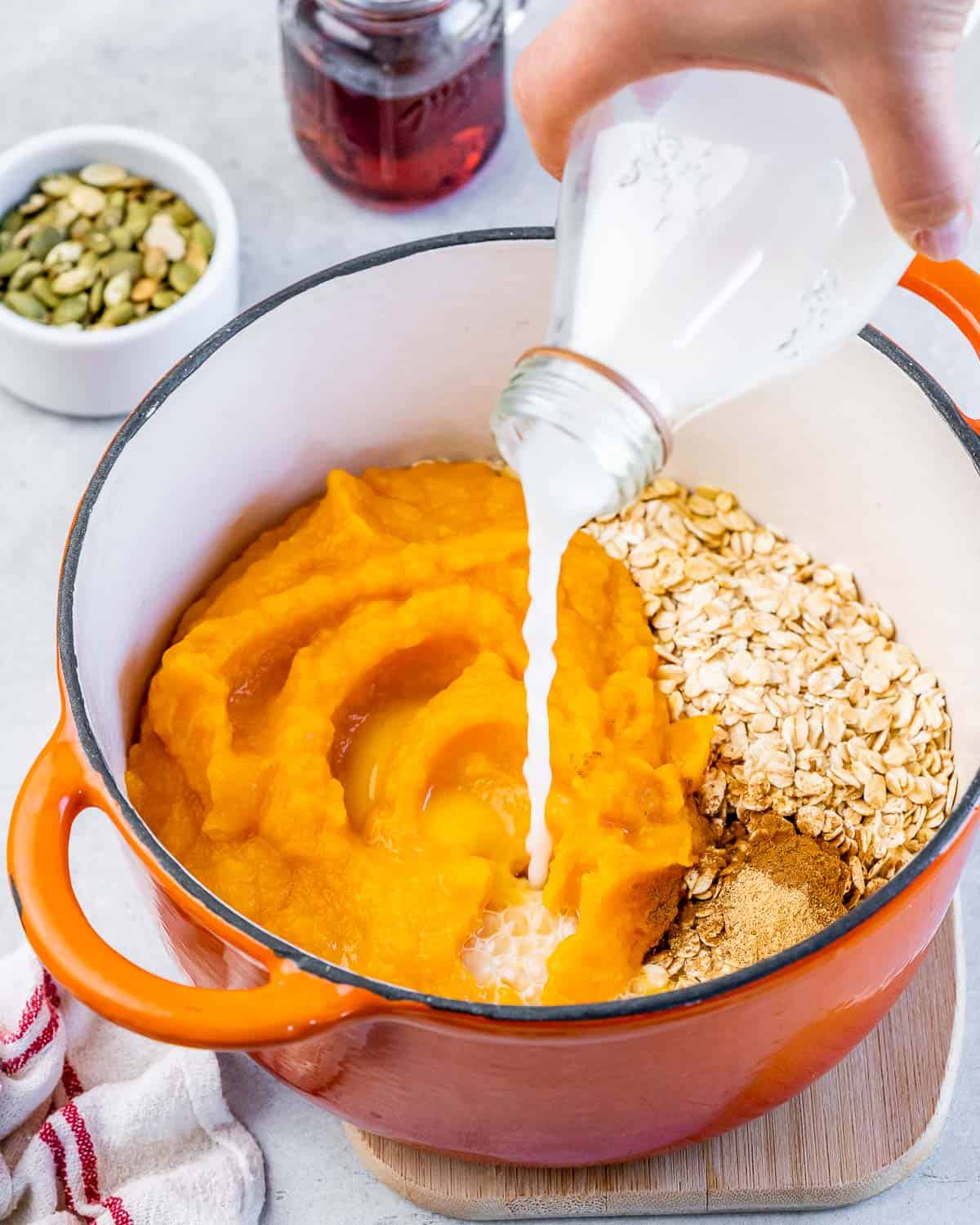 Pouring water into pot with pumpkin and oats.