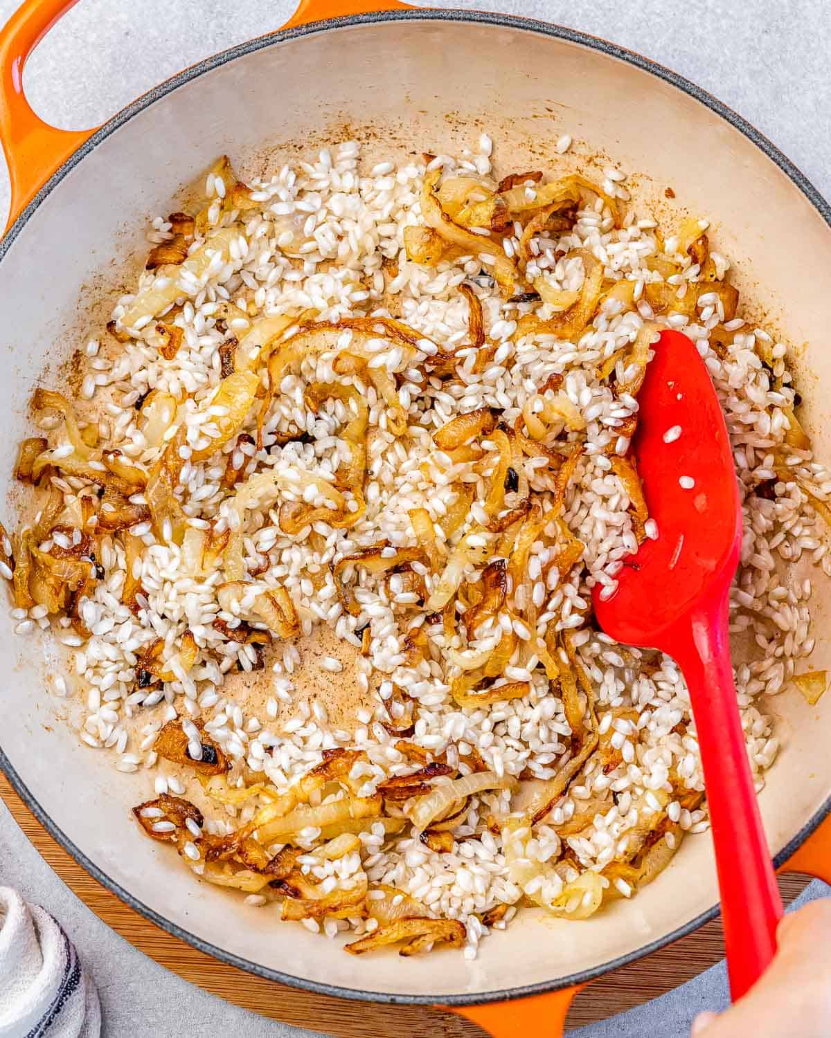 Stirring rice with caramelized onions in a pot.