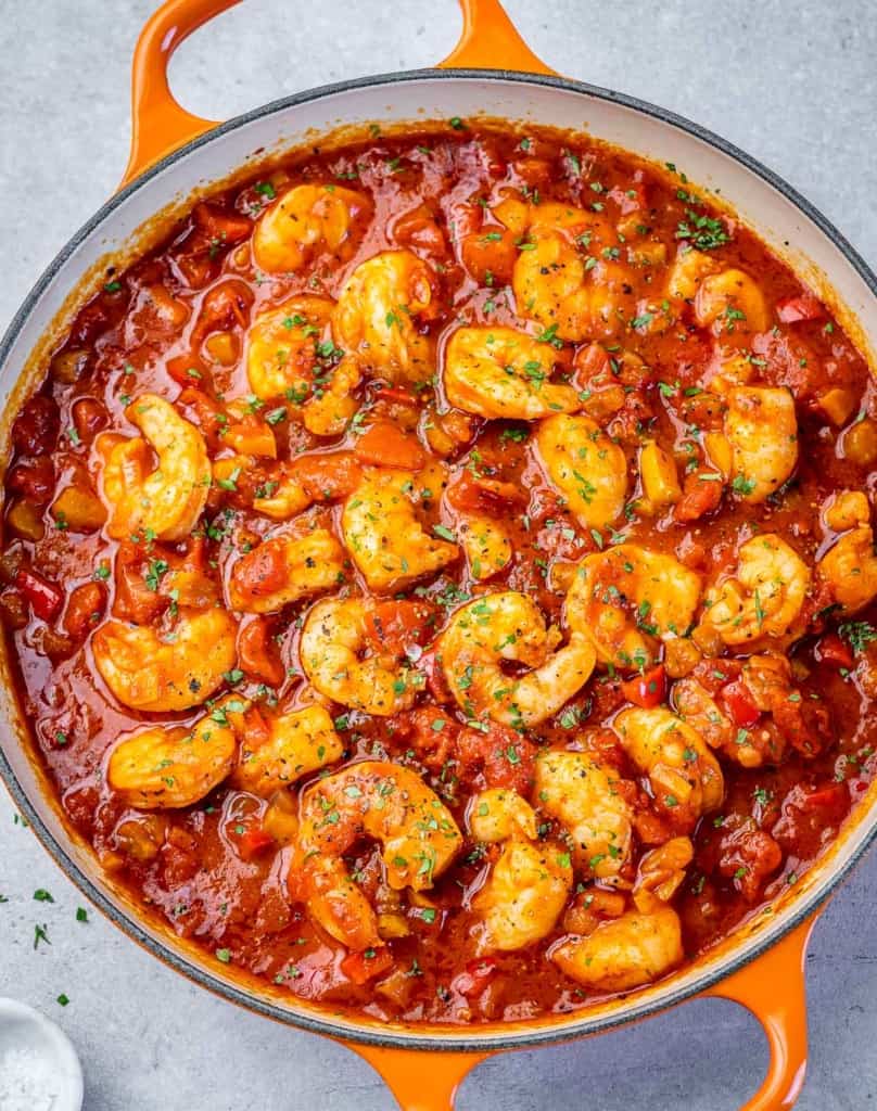 top view of orange skillet with shrimp in a red looking creole sauce 
