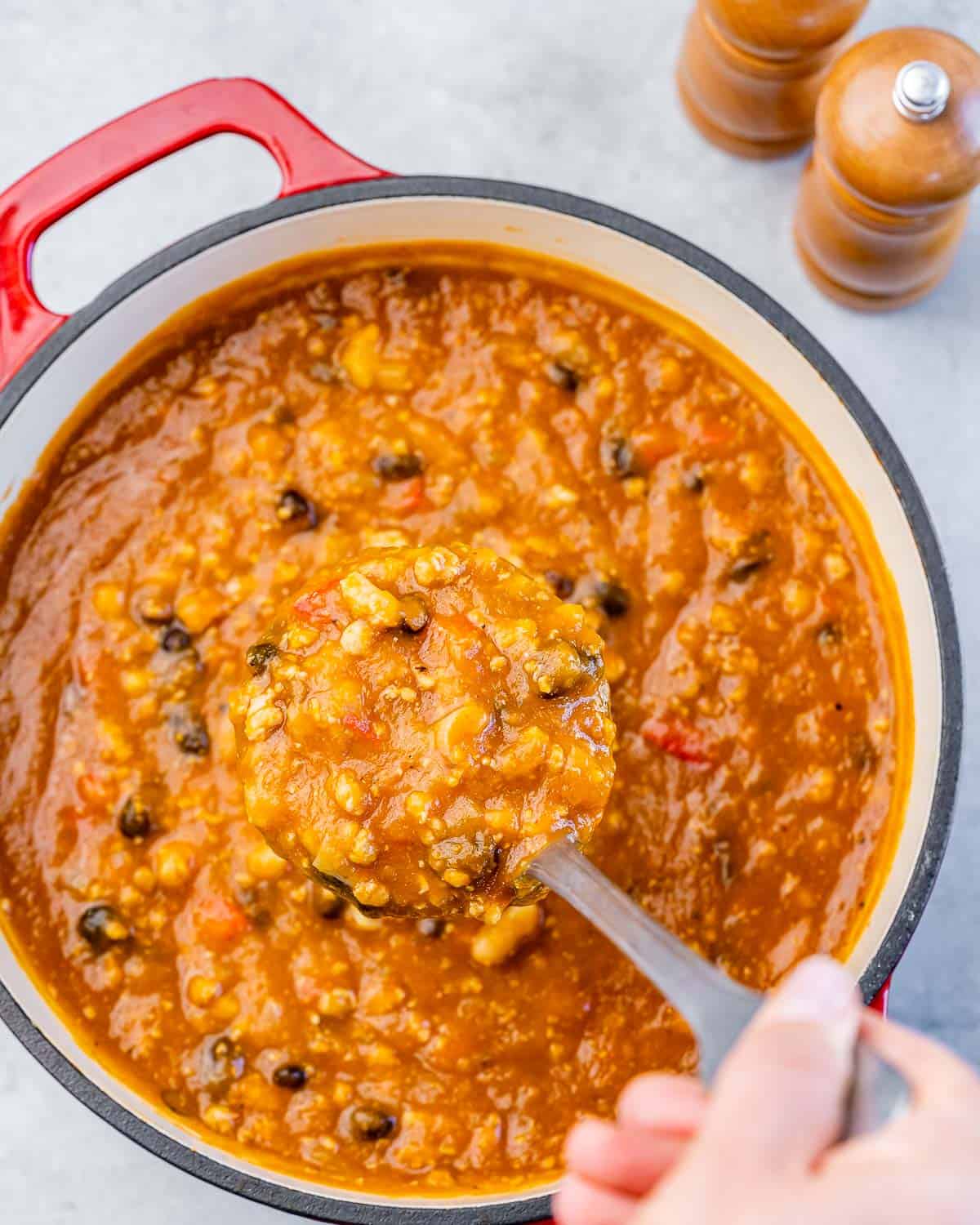 Ladling chili out of a large pot.