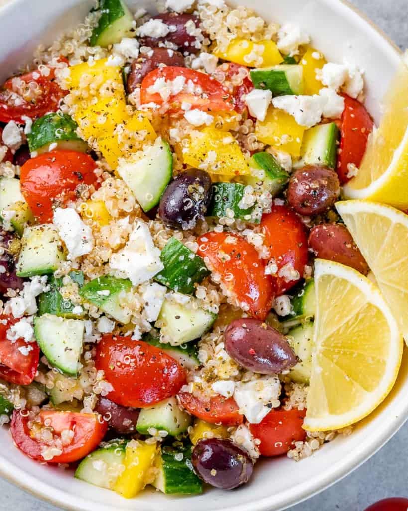close up image of quinoa salad loaded with veggies, olives, and feta cheese