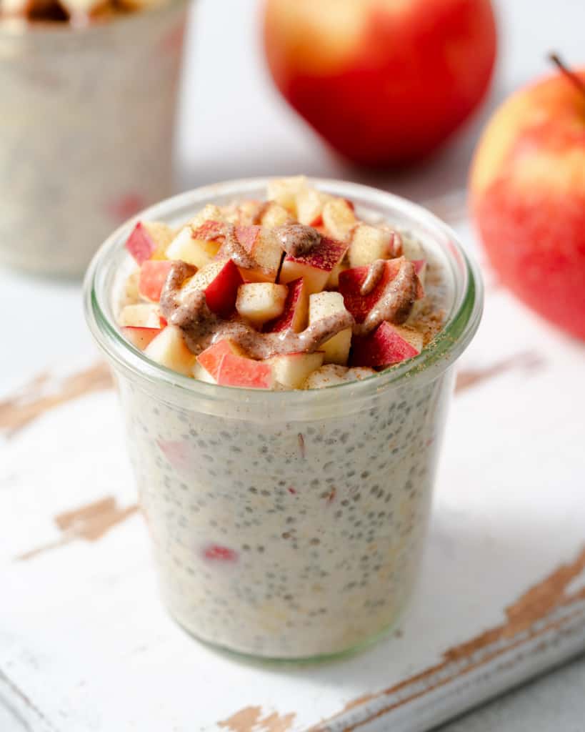top side shot of overnight oats in a jar topped with chopped apples and a drizzle of almond butter 