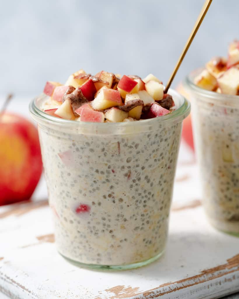 Side shot of a jar with overnight oats topped with chopped apples.