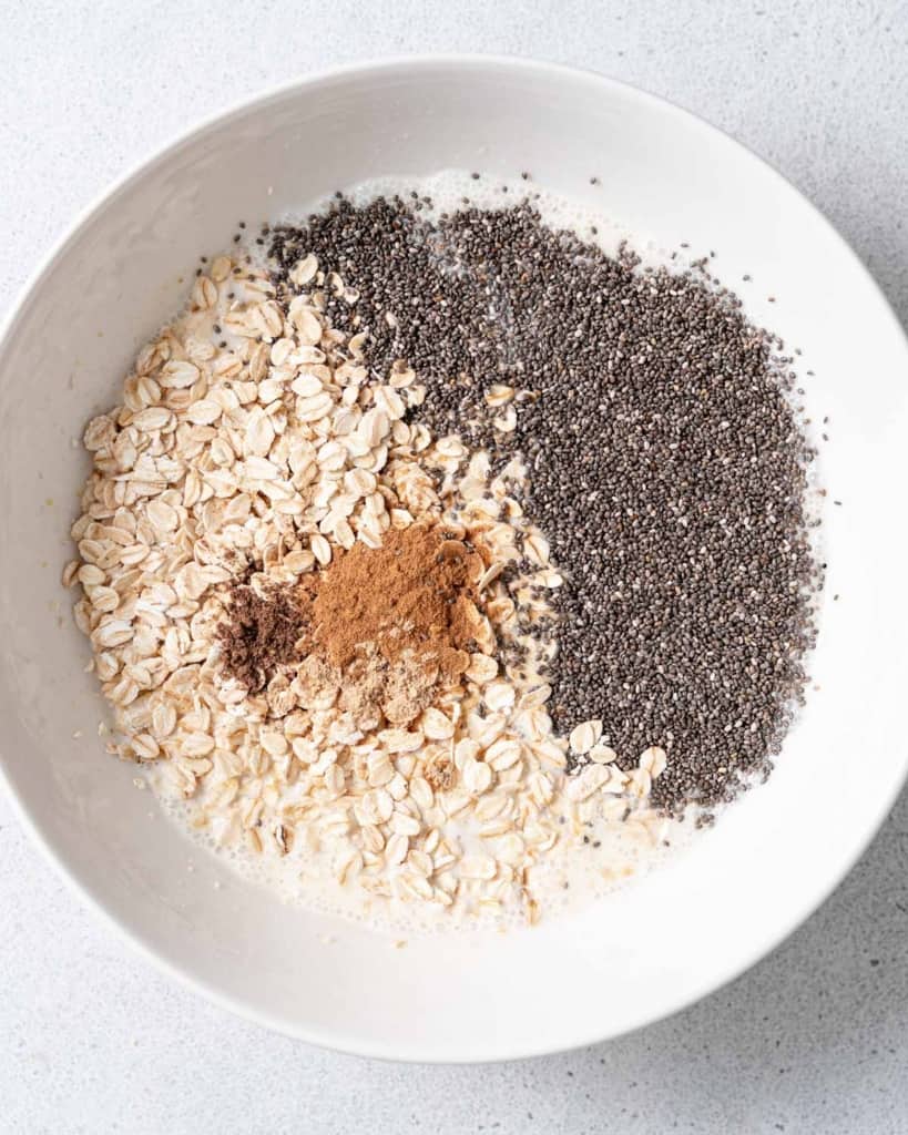 Oats, chia seeds and spices in a white bowl.