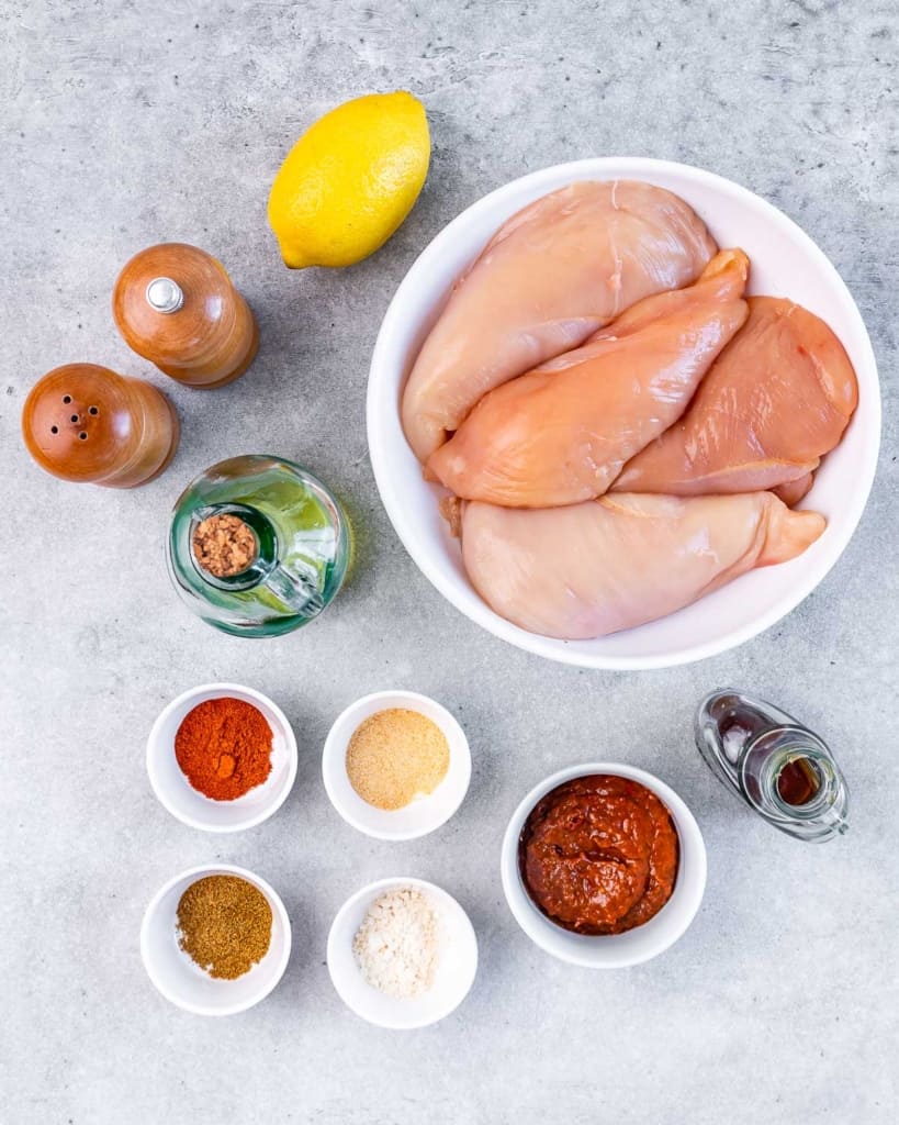 ingredients to make baked harissa chicken laid out on a flat surface 