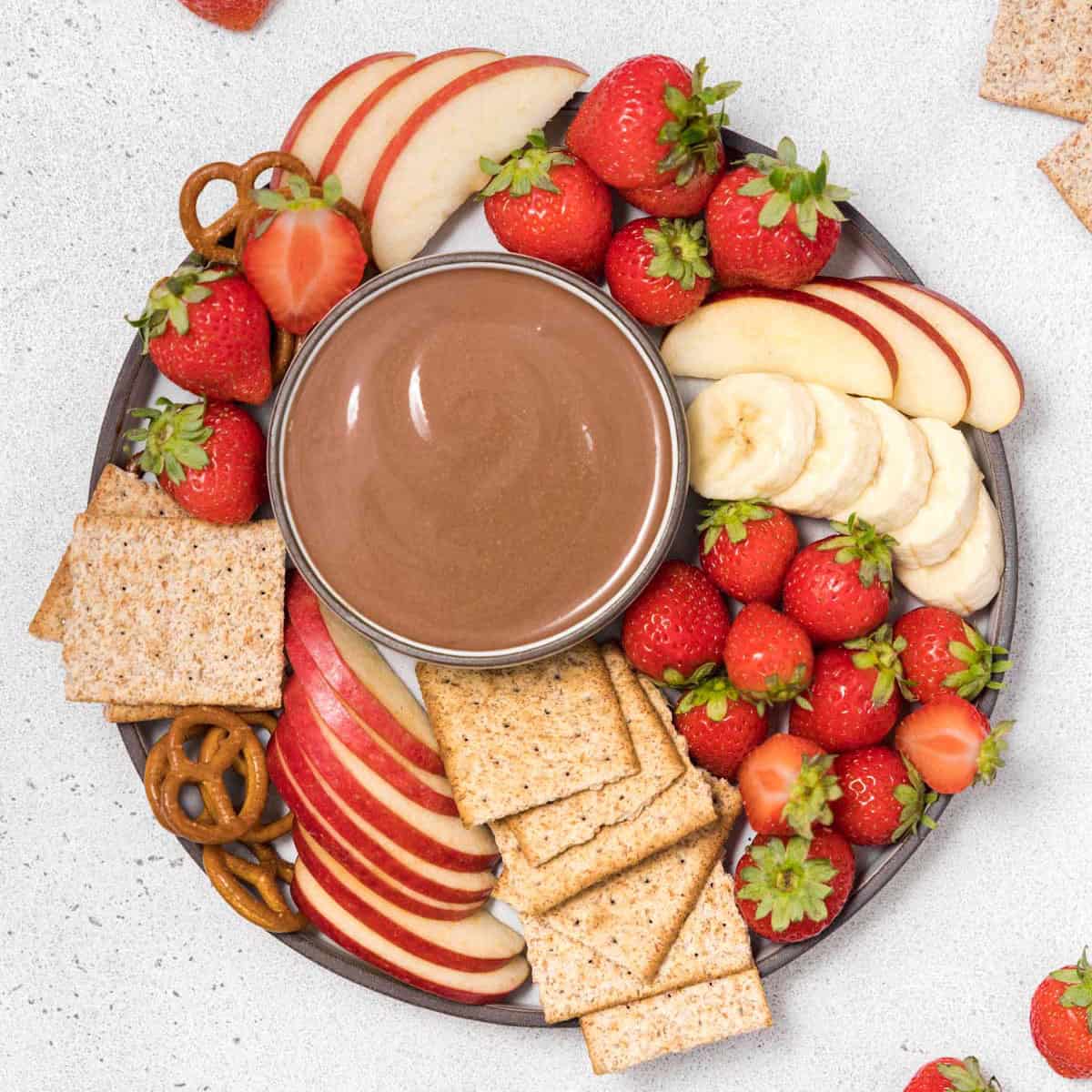 Top view yogurt dip in a bowl with crackers and fruits.